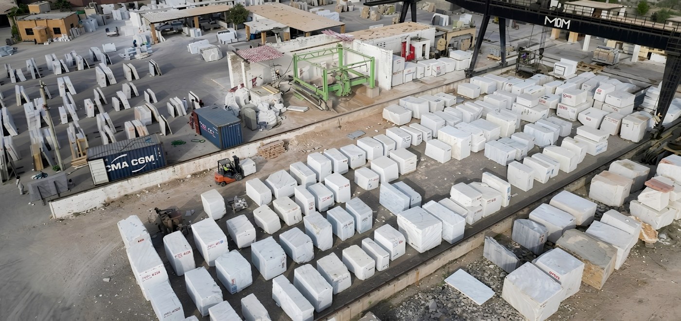 Large format natural stone slabs stacked in a wholesale yard showing veining variation across consecutive slabs
